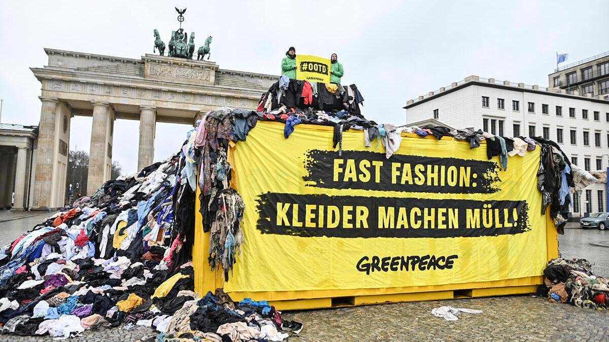 Protest mit Kleidermüll am Brandenburger Tor: Greenpeace bringt Textilmüll aus Ghana zur Berlin Fashion Week